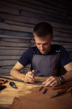 Working process of the leather belt in the leather workshop. Man holding Stock Photos