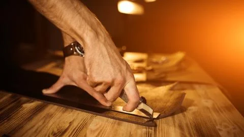 Working process of the leather belt in the leather workshop. Man holding tool Stock Photos