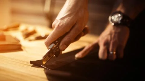 Working process of the leather belt in the leather workshop. Man holding tool Stock Photos