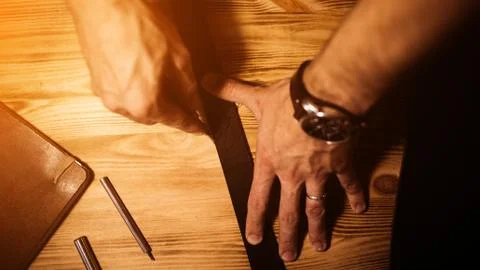 Working process of the leather belt in the leather workshop. Man holding tool Stock Photos