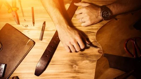 Working process of the leather belt in the leather workshop. Man holding hands Stock Photos