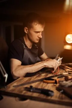 Working process of the leather belt in the leather workshop. Man holding Stock Photos