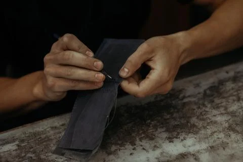 Working process of the leather wallet in the workshop. Man holding leather craft Stockfoto's