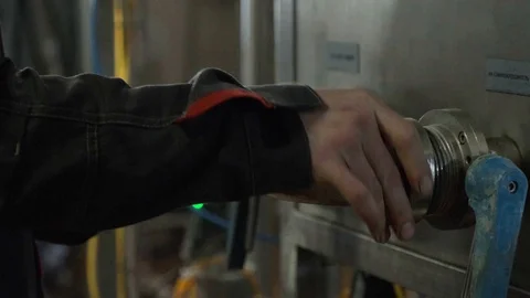 The working process. A man twists a pipe detail to a container. Splashing water. Video stock 127742564