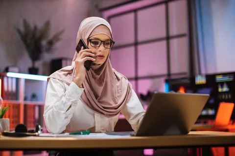 Working process at office of young muslim girl having phone call with partners 写真素材
