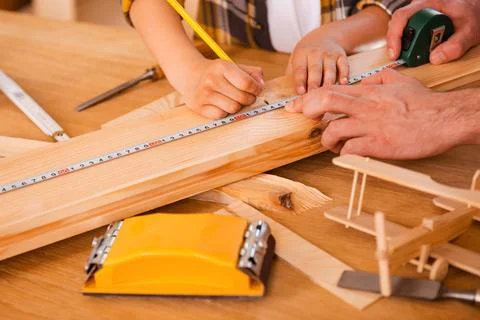 Working process. Seriousboy making measurements on the wooden plank while h.. Stock Photos