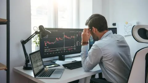 Working process. Smart male trader looking at charts on multiple computer Stock Photos