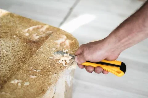 The working process of sofa restoration. A man's hand removes old foam rubber. Stock Photos