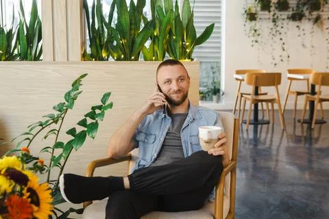 Working remotely while enjoying coffee in a modern cafe with plants and com.. Stock Photos