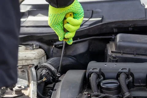 Working With a Screwdriver on a Car Engine in a Garage to Perform Maintenan.. Stock Photos