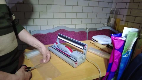 Working with a sealing machine at home in the evening to pack items for storage Video stock 332453279