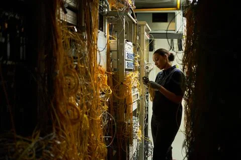 Working in Server Room with Network Cables and Equipment 写真素材
