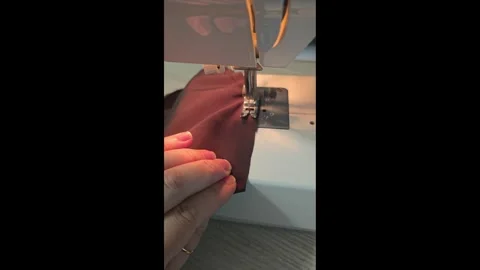 Working on a sewing machine. Sewing a lining from brown silk for a bag. Stock Footage 313860430