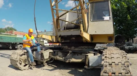 Working sitting on crawler cranes and eating potato chips. Video stock 52251495