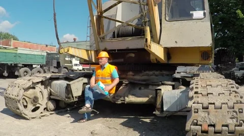 Working sitting on crawler cranes and eating potato chips. Video stock 52251621