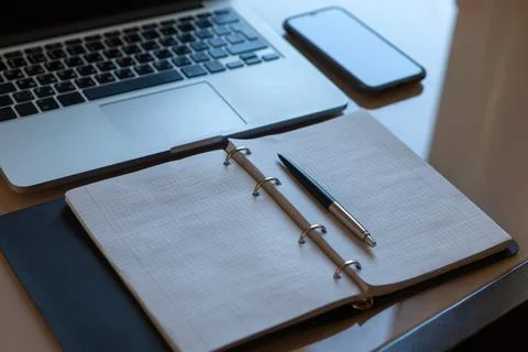 Working space, top view. Laptop, mobile phone and open notebook with pen on b Stock Photos