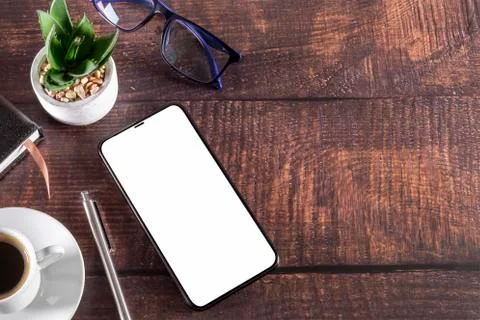 Working table with smart phone notepad coffee cup pen glasses plant on wooden Stock Photos