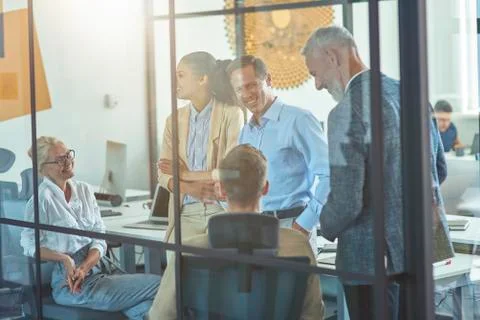 Working in team. Group of happy multi ethnic business people discussing work and Stock Photos