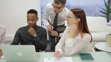 Working team is talking, sitting at desk with laptop in company. Video stock 85555310