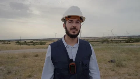 Working technical engineer looking at camera standing in a wind farm. Worker in Stock Footage 220999312