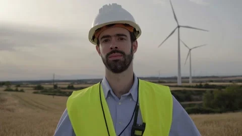 Working technical engineer looking serious at camera standing in wind farm Stock Footage 240083775