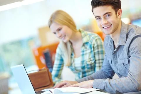 Working on their essays. Two smiling students helping each other with their Stock Photos