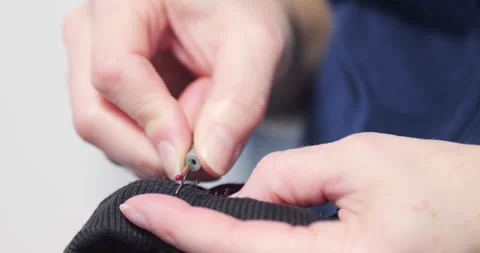 Working with a thread tool on old pyjamas 4K video Stock Footage 297535857