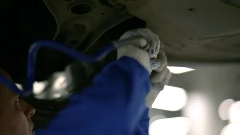 Working tool twists the screws in the protective sheet on the bottom of the car Stock Footage 80469921