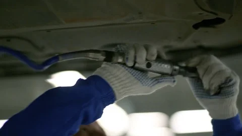 Working tool twists the screws in the protective sheet on the bottom of the car Stock Footage 80469923
