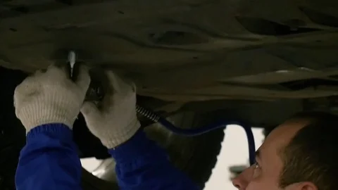 Working tool twists the screws in the protective sheet on the bottom of the car Stock Footage 80508119