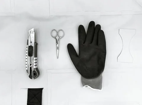 Working tools: stationery knife, scissors, glove. Top view. Black and white Stock Photos