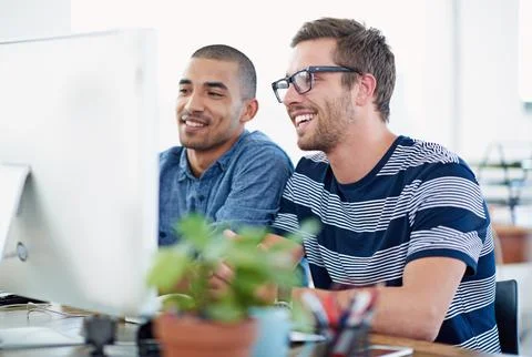 Working towards the same goal. two colleagues working together at a computer. Stock Photos
