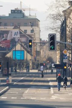 Working traffic lights on nearly empty streets with few cyclists and pedestrians Stock Photos