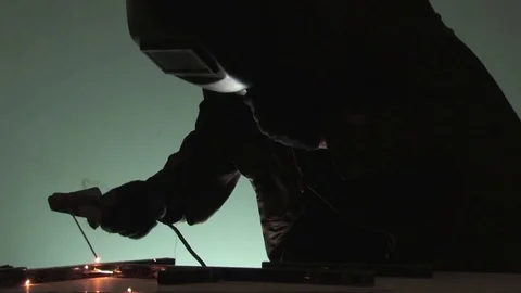 A working welder in an old closed welding mask performs welding work with electr Stock Footage 81003249