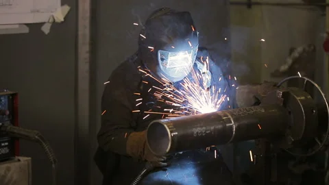 The working welder processes the metal, prepares the base. A man in a protective Stockbeeldmateriaal 87951388