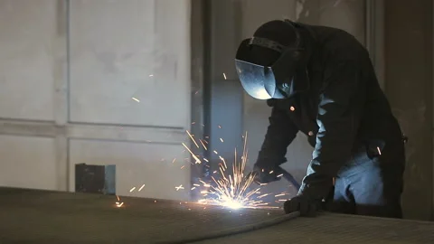 The working welder processes the metal, prepares the base. A man in a protective Video stock 87952515
