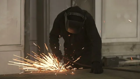 The working welder processes the metal, prepares the base. A man in a protective Stockbeeldmateriaal 87952541