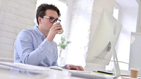 Working Young Man Drinking Coffee and using Desktop Stock Photos