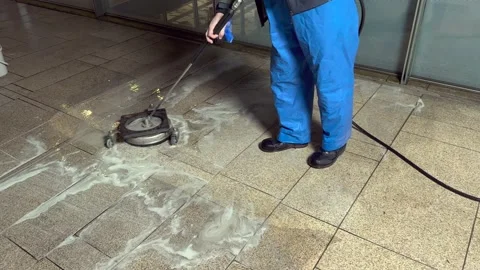 A workman cleans a dirty beige granite floor with a high pressure cleaner Stock Footage 236801842