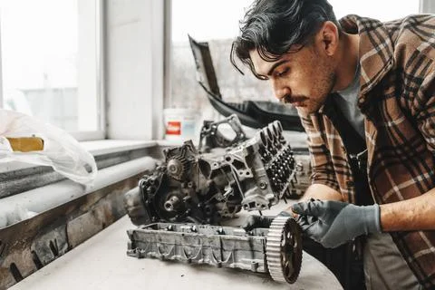Workman disassembling car engine at the working table of the car service garage Stock Photos