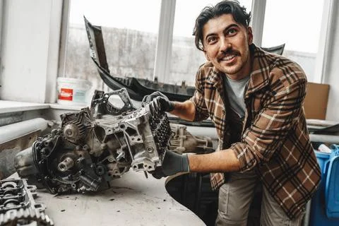 Workman disassembling car engine at the working table of the car service garage Stock Photos