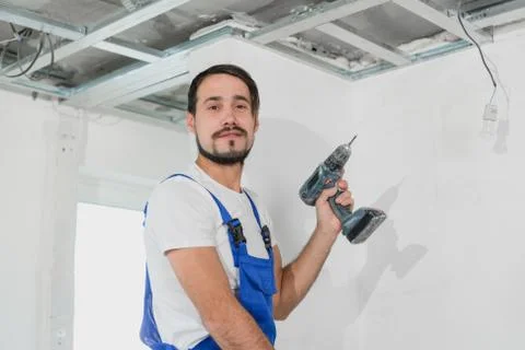 Workman with a drill and in uniform looking at the camera Stock Photos