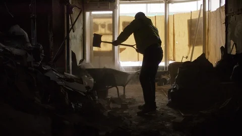 Workman emptying rubble from a building into a wheelbarrow, in slow motion Stock Footage 110807023
