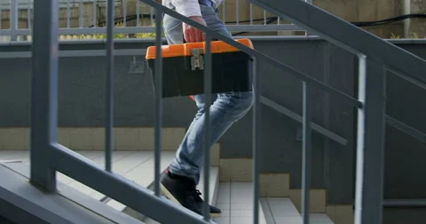 Workman with equipment walks down stairs from construction site Stockbeeldmateriaal 258503846