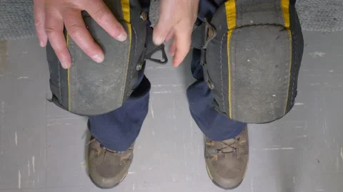 Workman fastening knee pads over blue workwear / overalls. Stock Footage 138239463