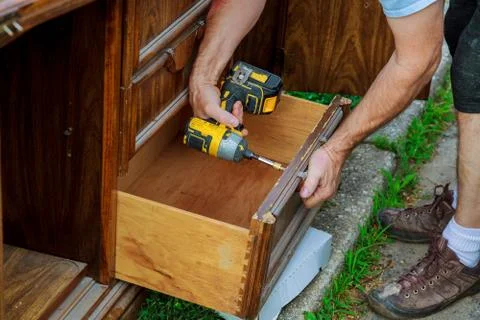 A workman fixing cabinet with screwdriver in kitchen Stock Photos