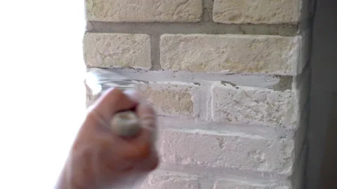 Workman in gloves staining decorative stone tiles with white colour using soft 스톡 동영상 233643080