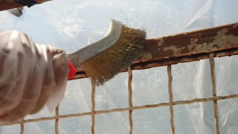 Workman in gloves using metal brush for old paint and rust removing. Process of Stock Footage 208442116