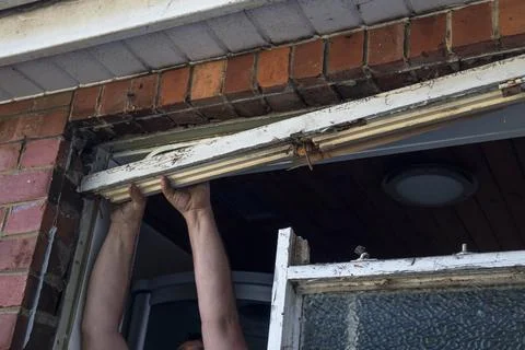 Workman holding up a crowbar ready to remove part of old wooden window frame Stock Photos