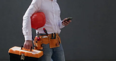 Workman holds toolbox in hands checking message on phone Video stock 258739160